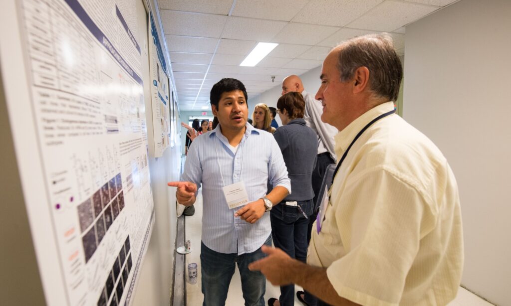 Attendees talk in front of research posters